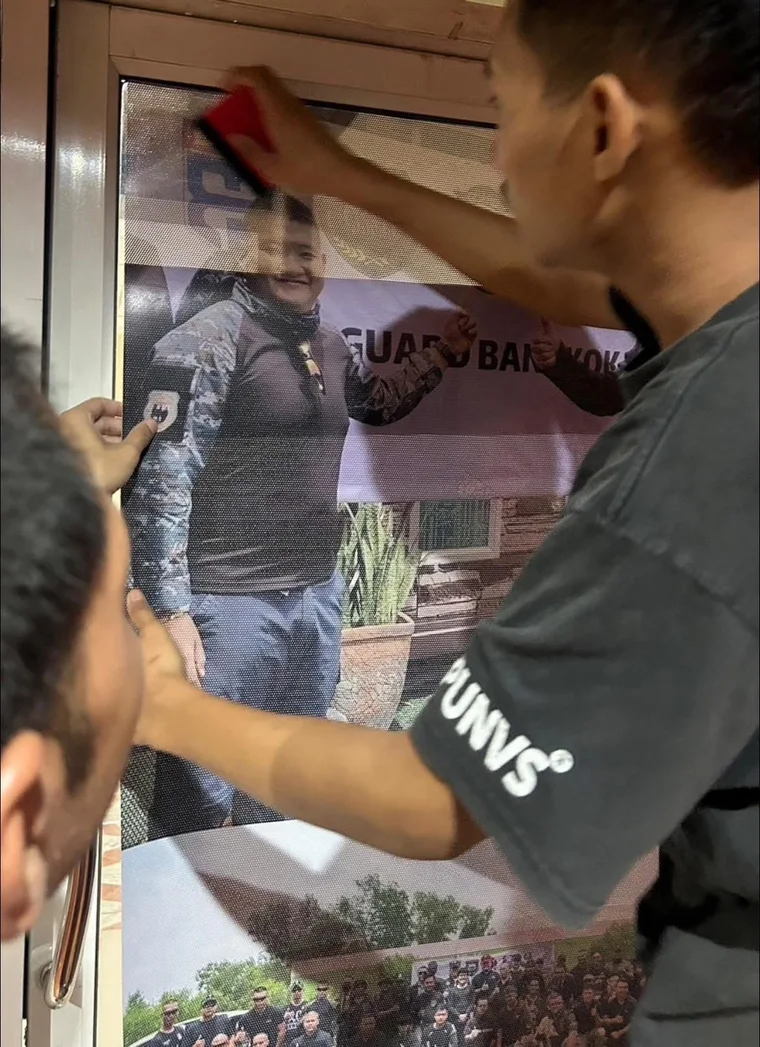 บุคคลกำลังติดตั้งสื่อภาพบนบานประตู